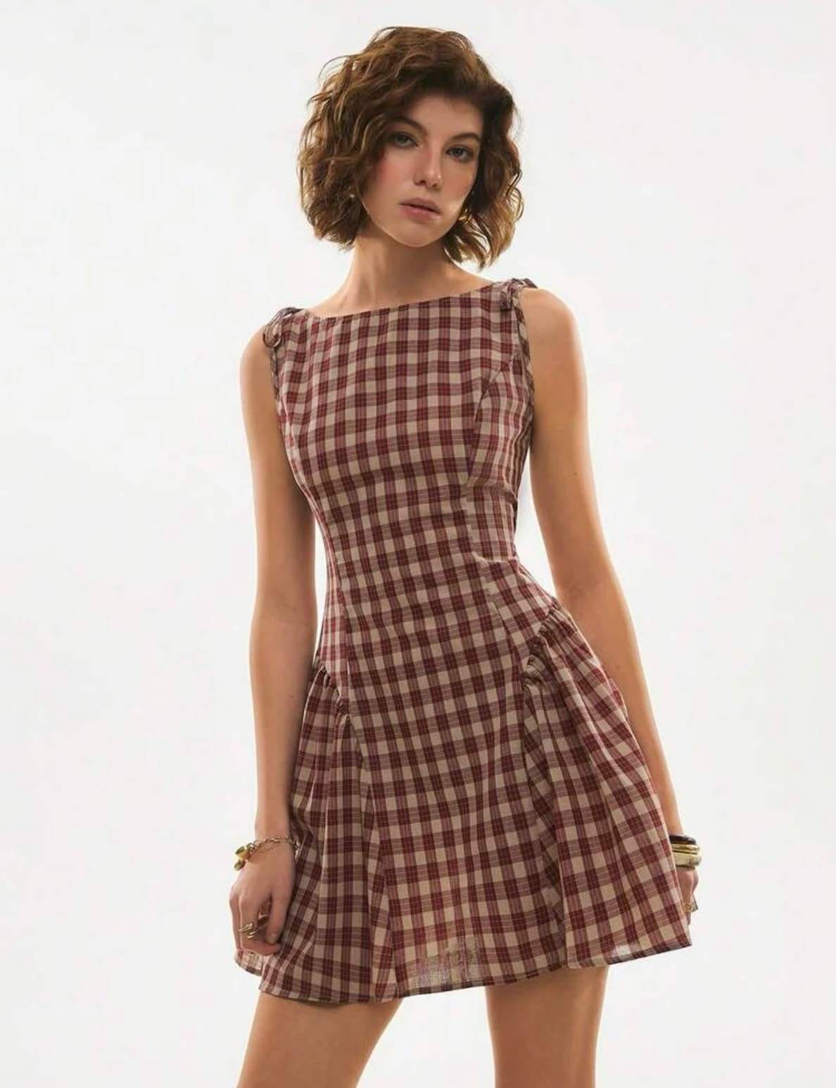 A woman in the red and cream check Ophelie Dress, a Christmas outfit, sleeveless with a fitted waist and flared short skirt.