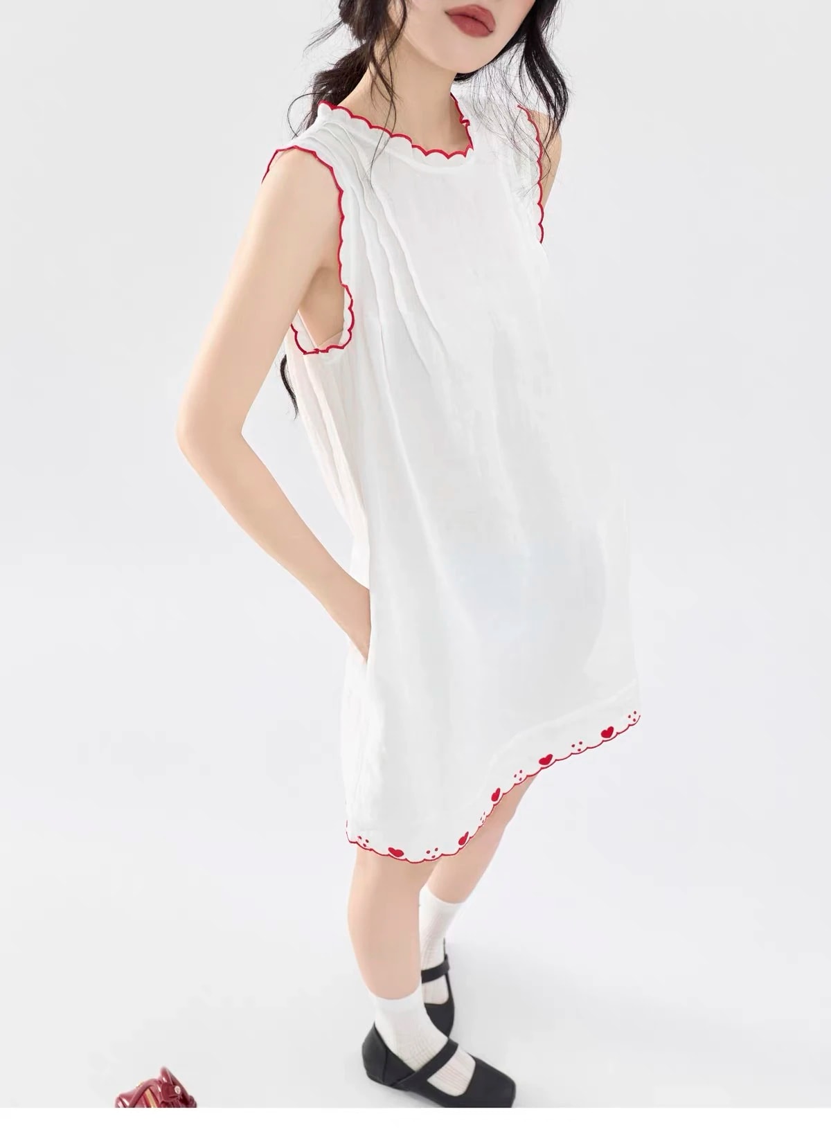 Close-up of the Lucie Dress: soft pleats at the shoulder, red scalloped neckline and heart hem.