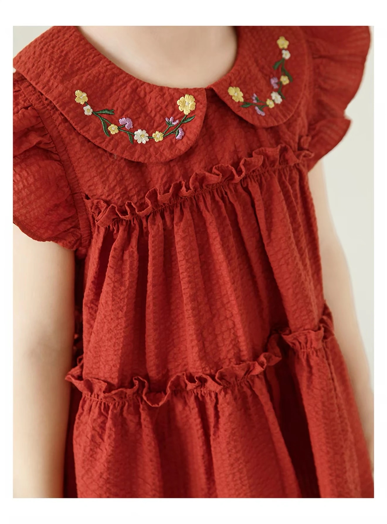 Close-up of the Fleur Set's red cotton top: floral embroidered collar, ruffled sleeves and tiered ruffles.