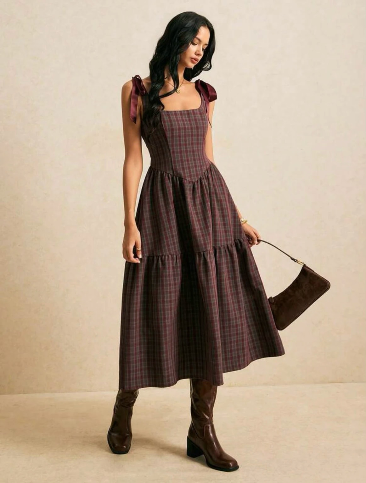 A woman in the wine-red tartan Juliette Dress, a Christmas outfit, with satin bow straps and a tiered midi skirt.