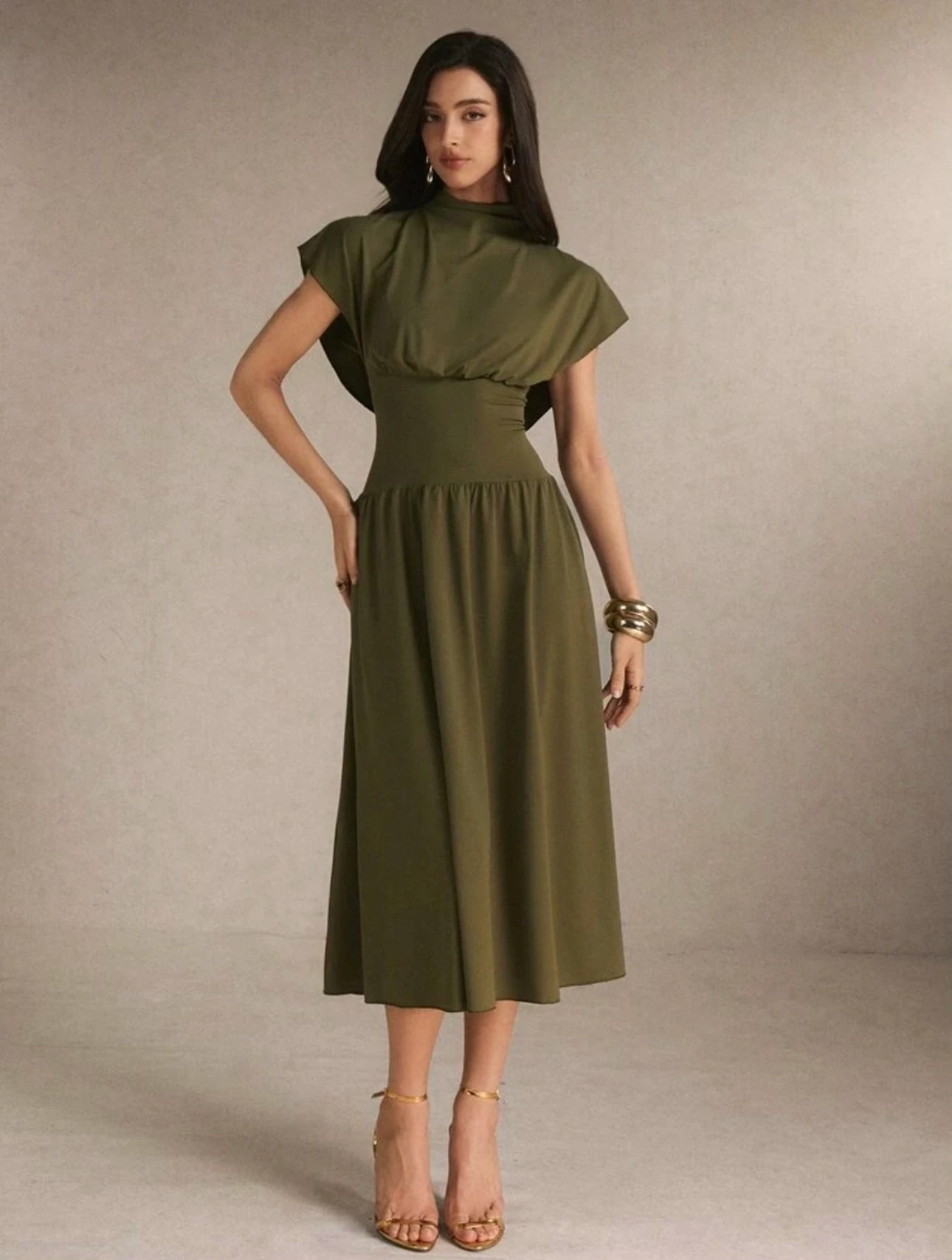 A woman in the olive green Camille Dress, a Christmas outfit, with a draped stand collar, wide cap sleeves, a fitted waist and a gathered midi skirt.