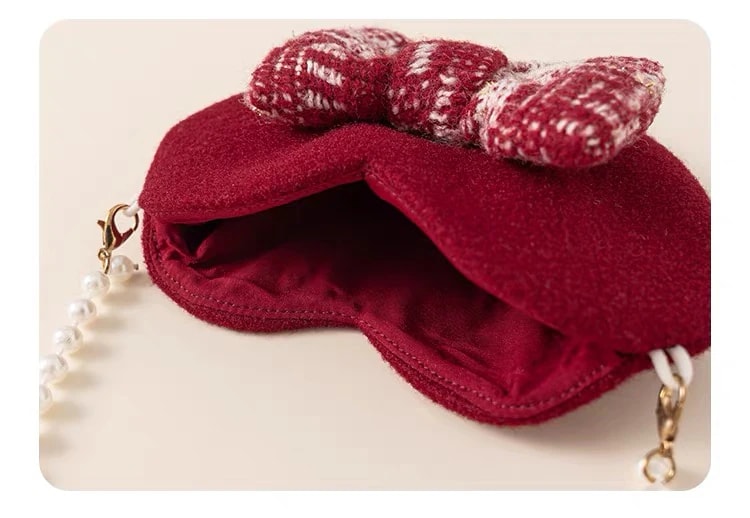 The Delphine Dress heart mini bag opened to show its lined inside and the pearl strap clasps.