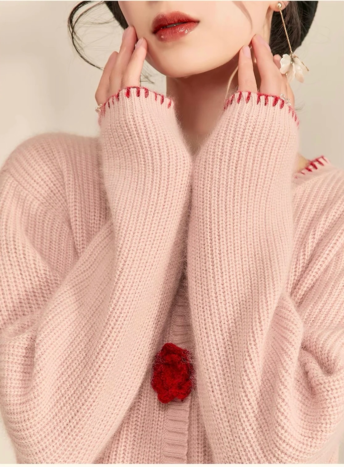 Detail lengan rajut rib pink lembut dengan jahitan tepi merah di ujung lengan.