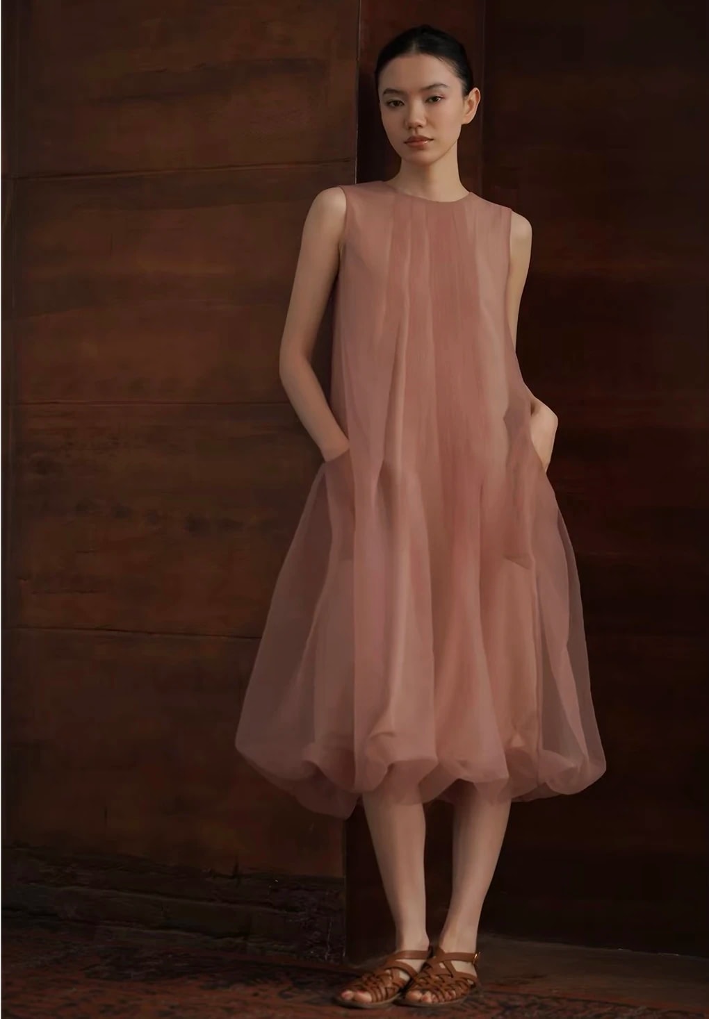 Front view of the sleeveless Solene Dress with hands in the side pockets and the gathered bubble hem.