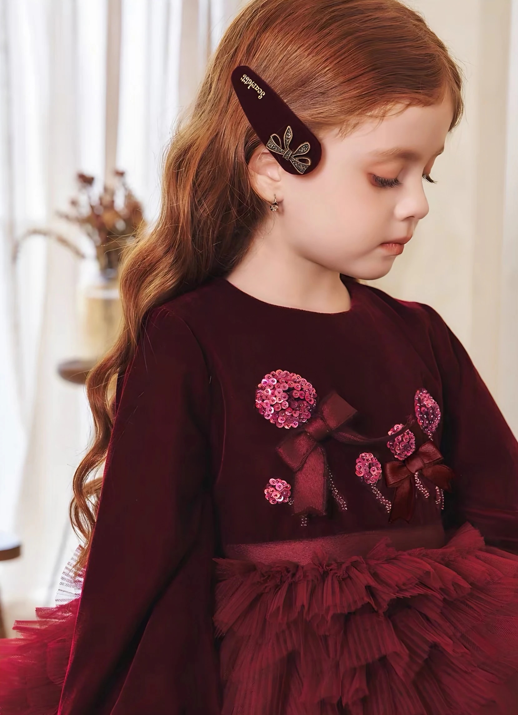 Detail atasan Eleonore Dress: hiasan bunga payet pink dan pita kecil burgundy di kain seperti beludru.