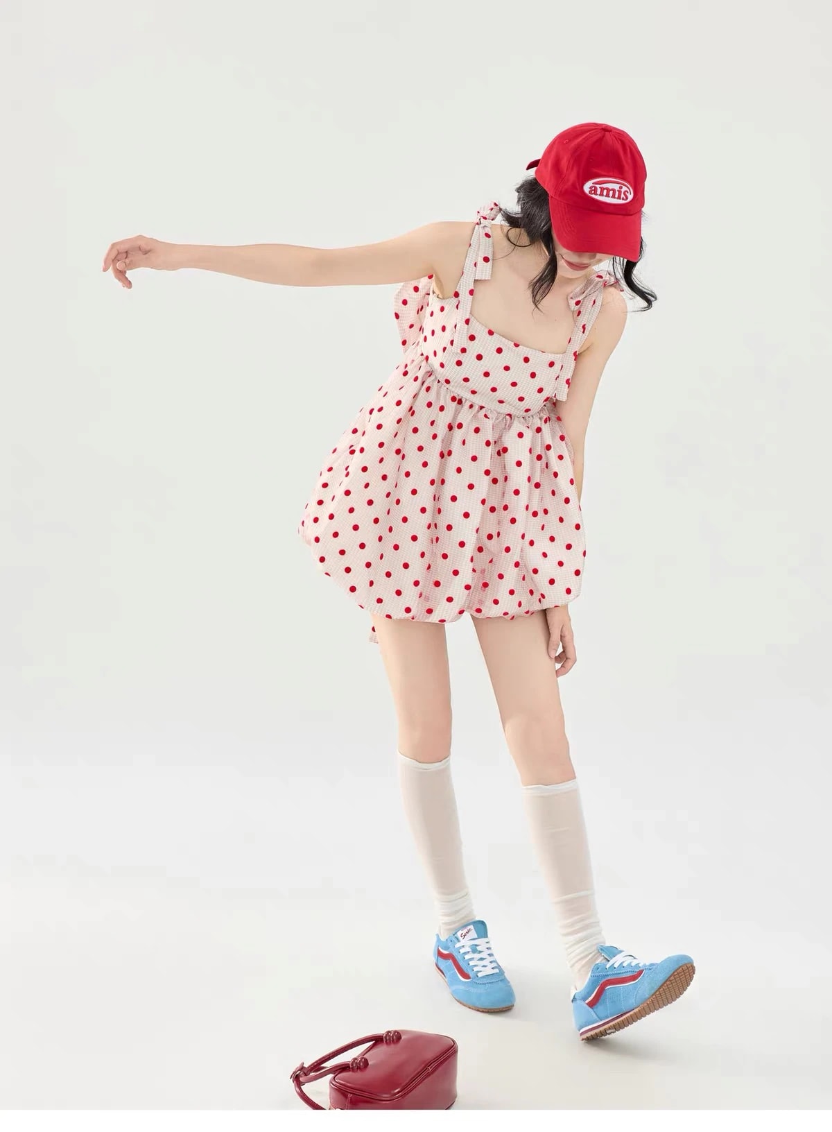 Pose ceria memakai Josette Dress dengan satu tangan terentang, kaus kaki putih selutut, dan sneakers biru.