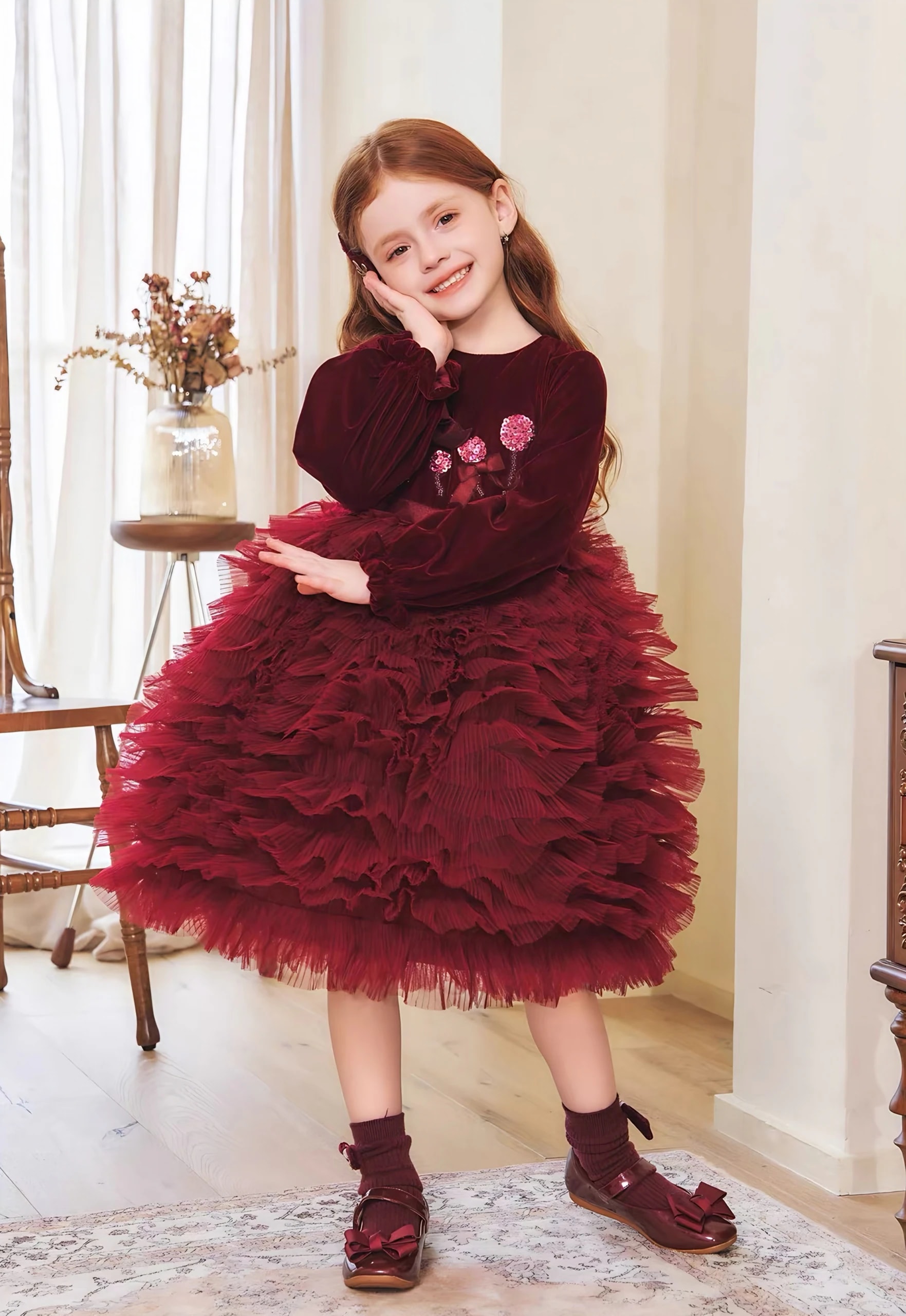 Berpose dengan tangan di pipi memakai Eleonore Dress, terlihat ujung lengan berkerut dan rok tulle yang mengembang.
