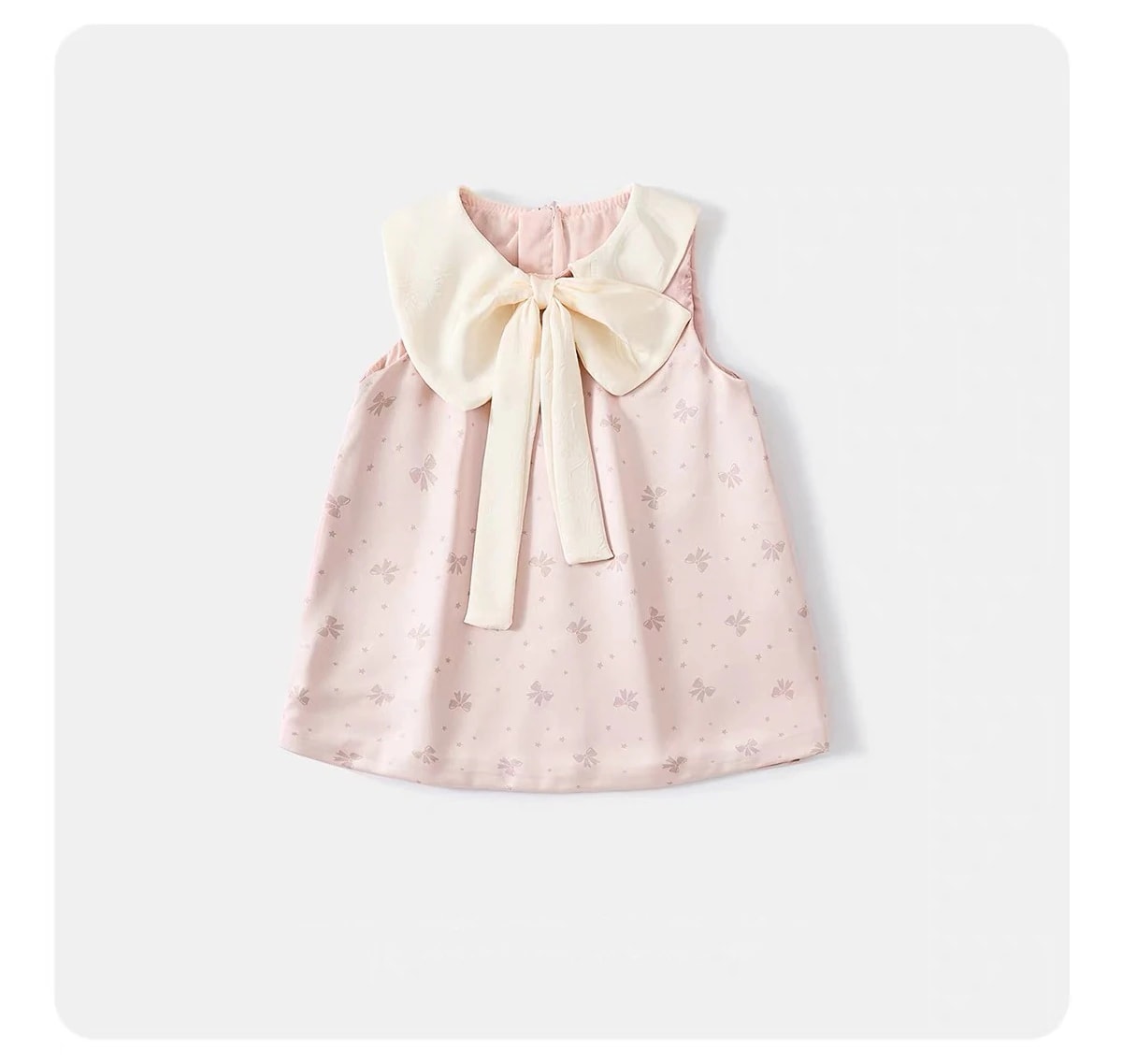 Flat lay Amelie Dress tampak depan: potongan tanpa lengan warna pink lembut, motif pita, dan pita satin gading besar.