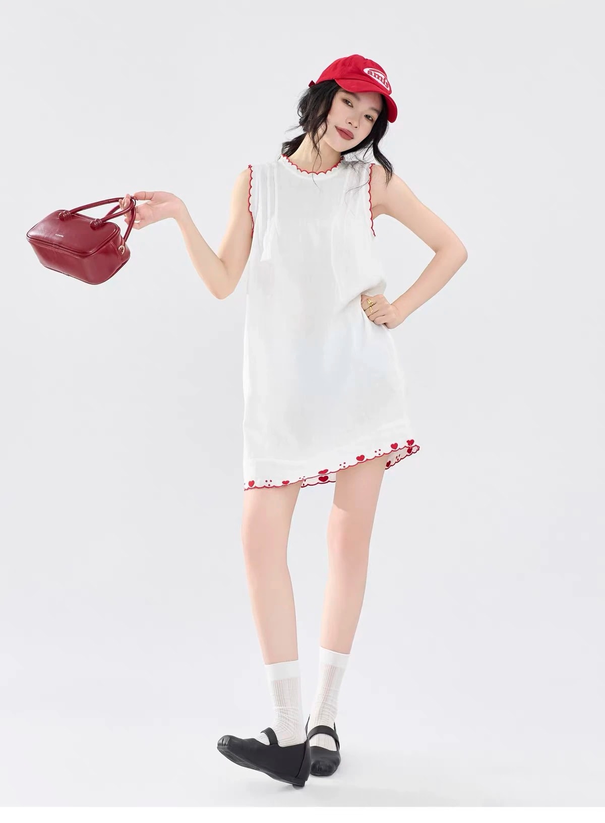 Full-length front view of the Lucie Dress with white socks and black shoes, holding a red bag.