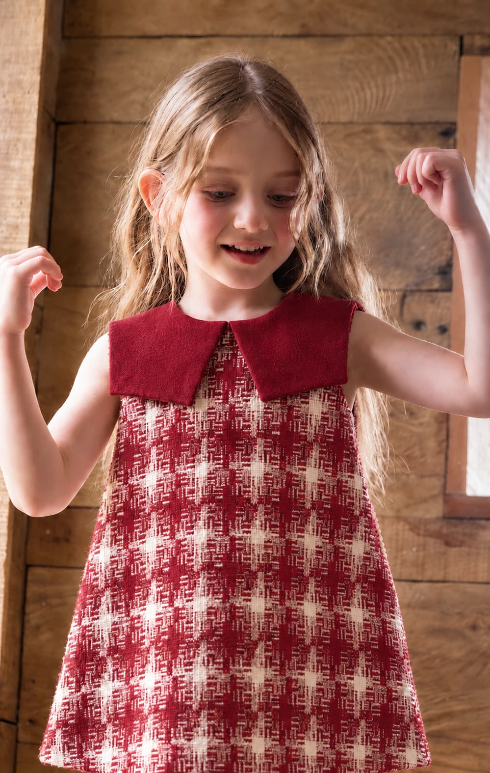 Close-up of a girl in the Delphine Dress with arms raised, showing the plain burgundy collar over the tweed bodice.
