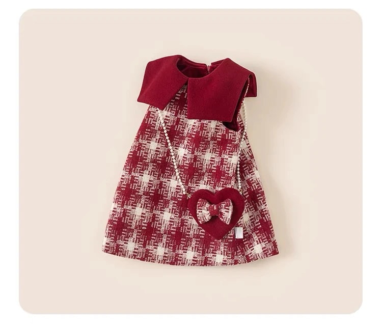 Delphine Dress dibentangkan agak miring, terlihat bentuk A-line tanpa lengan dan tas mini hati di bagian depan.