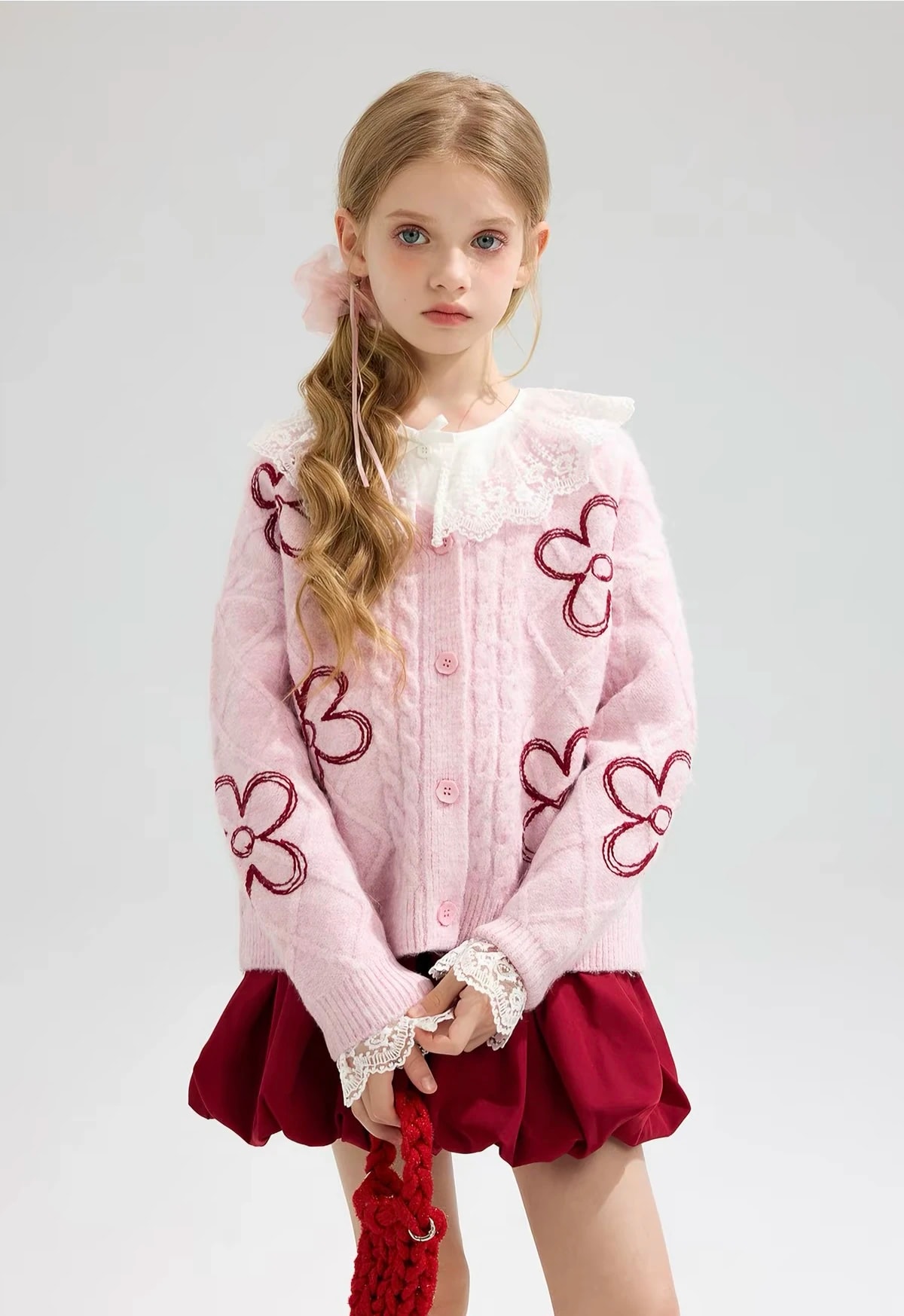 Tampak depan anak perempuan memakai Clemence Cardigan yang dikancing, terlihat kancing pink dan bordir bunga.