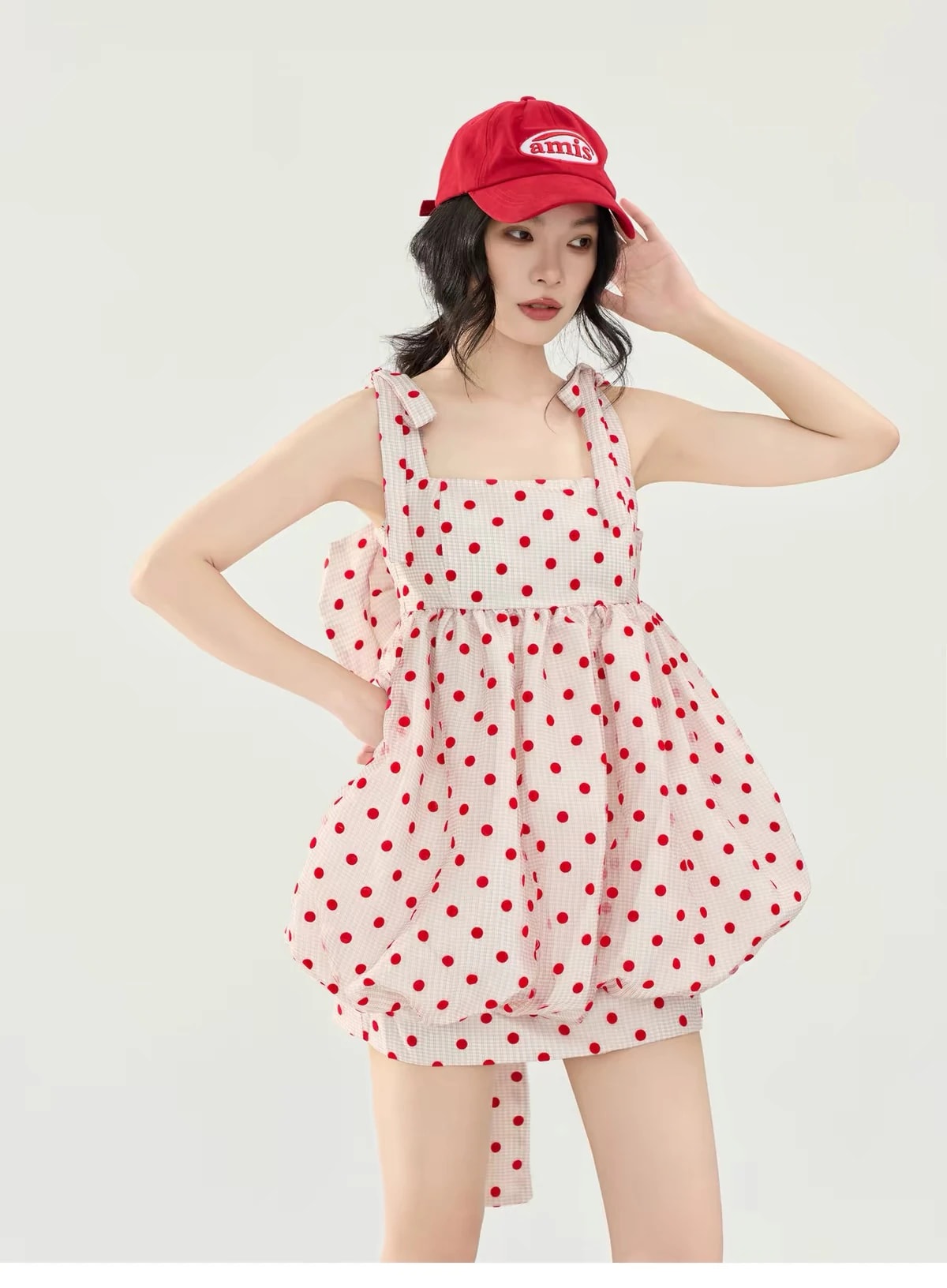 A woman in the red polka dot Josette Dress on pink gingham, a Christmas outfit, with tie straps and a bubble skirt.